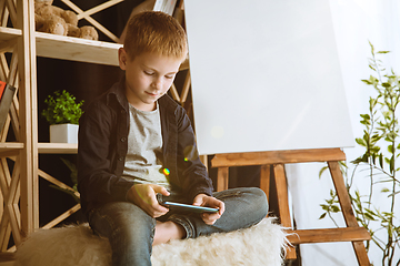 Image showing Little boy using different gadgets at home