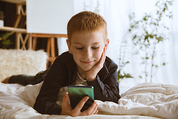 Image showing Little boy using different gadgets at home