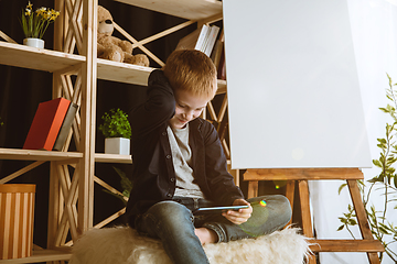 Image showing Little boy using different gadgets at home