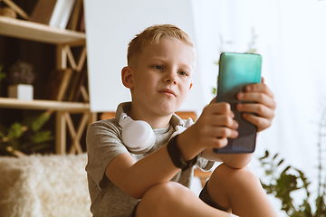 Image showing Little boy using different gadgets at home