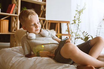 Image showing Little boy using different gadgets at home