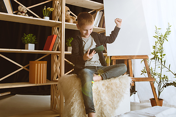 Image showing Little boy using different gadgets at home