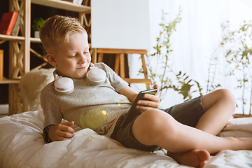 Image showing Little boy using different gadgets at home