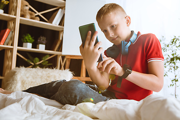 Image showing Little boy using different gadgets at home