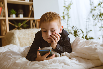 Image showing Little boy using different gadgets at home