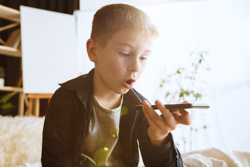 Image showing Little boy using different gadgets at home