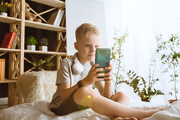 Image showing Little boy using different gadgets at home