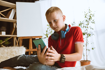 Image showing Little boy using different gadgets at home