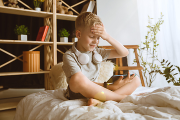 Image showing Little boy using different gadgets at home