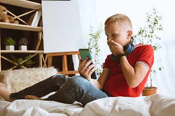 Image showing Little boy using different gadgets at home