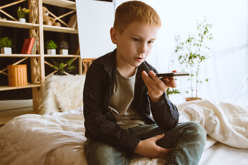 Image showing Little boy using different gadgets at home