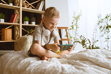 Image showing Little boy using different gadgets at home