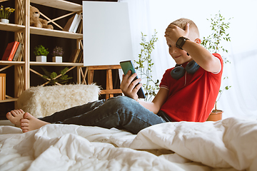 Image showing Little boy using different gadgets at home