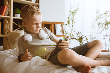 Image showing Little boy using different gadgets at home