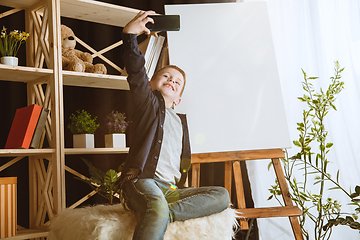 Image showing Little boy using different gadgets at home