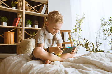 Image showing Little boy using different gadgets at home