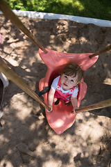 Image showing little girl swinging  on a playground