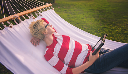 Image showing woman using a tablet computer while relaxing on hammock