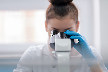 Image showing female student scientist looking through a microscope