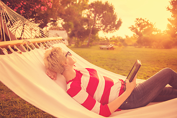 Image showing woman using a tablet computer while relaxing on hammock