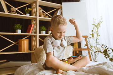 Image showing Little boy using different gadgets at home