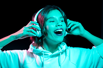 Image showing woman in headphones listening to music in neon