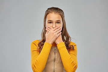 Image showing scared teenage girl closing her mouth by hands