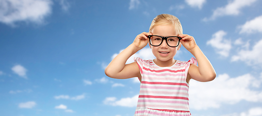 Image showing smiling little girl in glasses over sky background