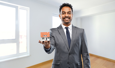 Image showing indian man realtor with house model at new home