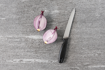 Image showing cut red onion and knife on slate stone background