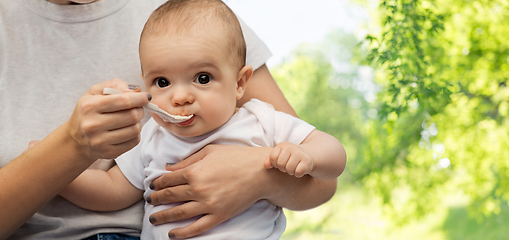 Image showing close up of mother with spoon feeding little baby