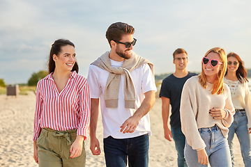 Image showing happy friends walking along summer beach