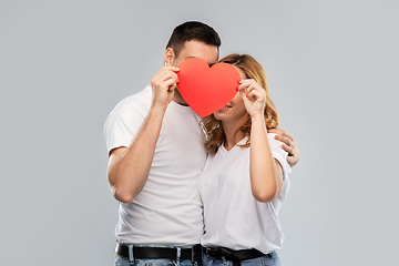 Image showing smiling couple hiding behind big red heart