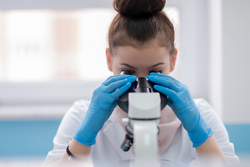 Image showing female student scientist looking through a microscope
