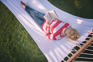 Image showing woman reading a book while relaxing on hammock