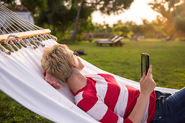 Image showing woman using a tablet computer while relaxing on hammock