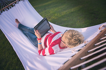 Image showing woman using a tablet computer while relaxing on hammock