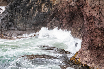 Image showing ocean wave on a red rock at New Zealand