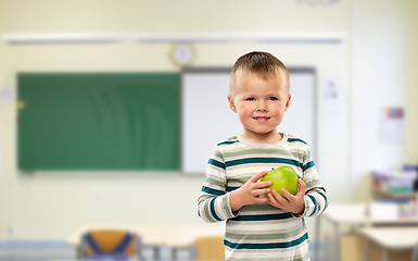 Image showing smiling boy holding green apple at school