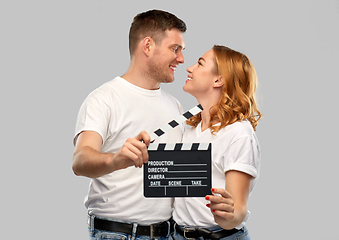 Image showing happy couple in white t-shirts with clapperboard