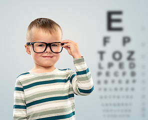 Image showing little boy in glasses over eye test chart