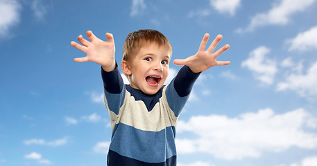 Image showing little boy making scary faces over sky background