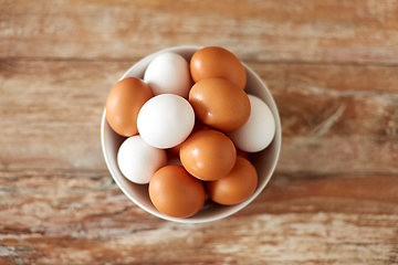 Image showing close up of eggs in ceramic bowl on wooden table