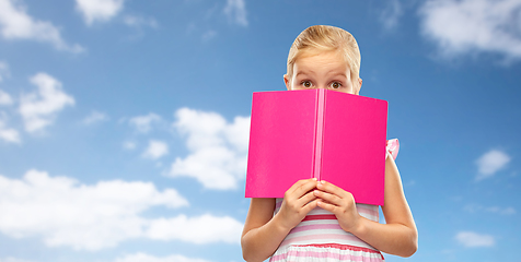 Image showing little girl hiding over book on sky background