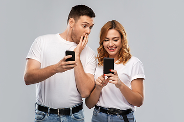 Image showing happy couple in white t-shirts with smartphones