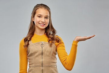 Image showing happy teenage girl holding something on empty hand