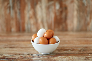 Image showing close up of eggs in ceramic bowl on wooden table