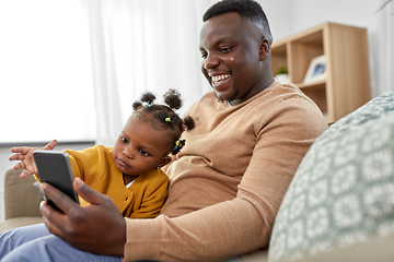 Image showing father with smartphone and baby daughter at home