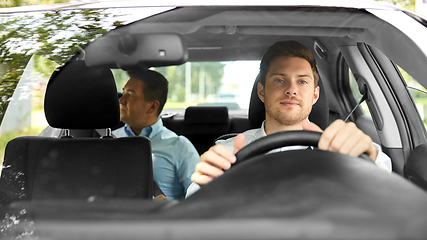 Image showing male taxi driver driving car with passenger