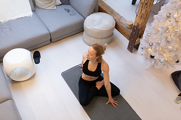 Image showing Beautiful blonde woman doing home workout indoors. Woman practice yoga at home. Fit girl using workout tutorials for healthy active lifestyle. Woman using quarantine for home workouts.